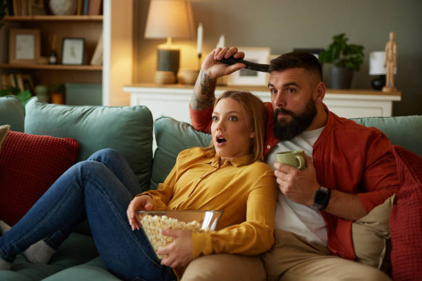istock Couple watching scary movie on sofa at home 1491440115