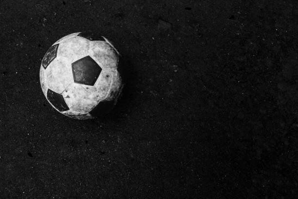 Close-up of soccer ball. It is on wet ground. Sports equipment is in black and white color.