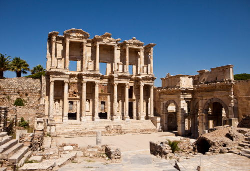 The front facade and courtyard of the library building at Ephesus is an imposing ancient Greek and Roman structure. Built from old stone and reconstructed by archaeologists, it is a popular tourist stop near the city of Izmir in Turkey.