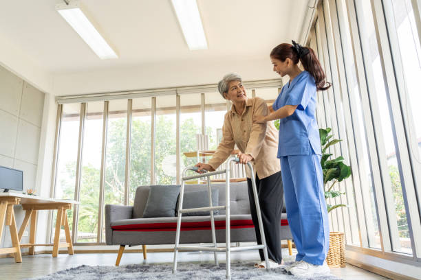istock Young physical therapist female help aged female patient walk with walker 1491444300