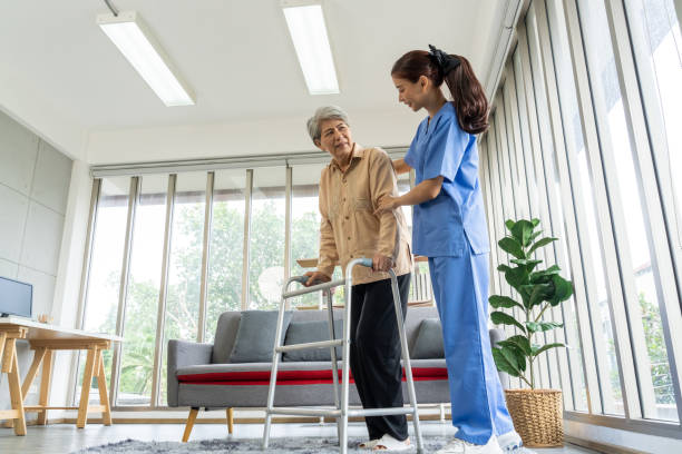istock Young physical therapist female help aged female patient walk with walker 1491444313