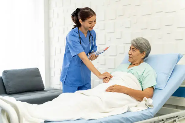 Photo of Medical personnel visit female patient lying in bed to inquire about symptoms