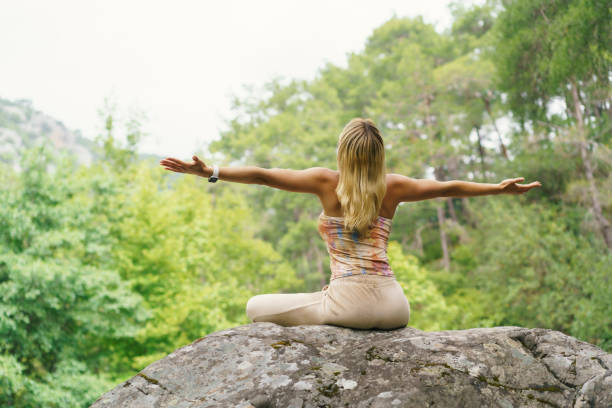 Attractive young woman practicing yoga and meditation in forest