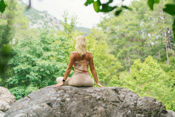 Attractive young woman practicing yoga and meditation in forest