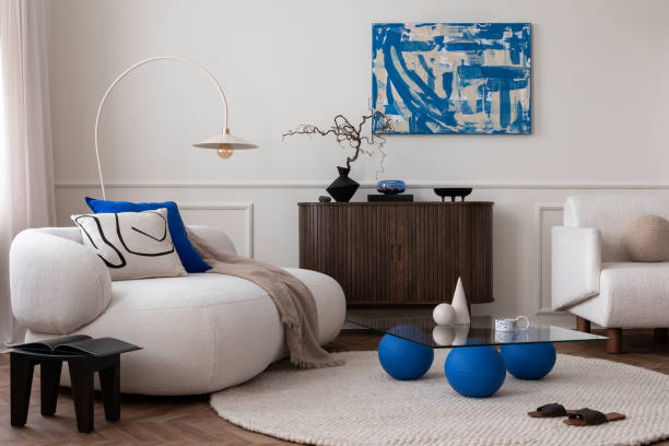 istock Modern composition of living room interior with mock up poster frame, glass coffee table, stylish sofa, white armchair, wooden sideboard, round rug and personal accessories. Home decor. Template. 1491447503