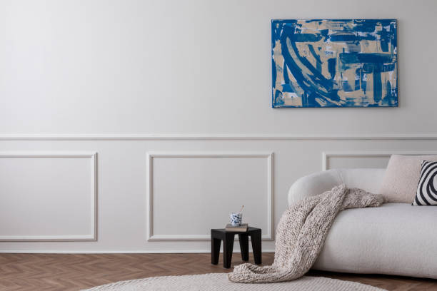 istock Modern composition of living room interior with copy space, mock up poster frame, stylish sofa, wooden stool, beige pillow, cup , round rug and personal accessories. Home decor Template 1491447594
