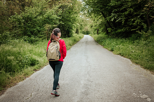 Mature female backpacker walking on forest path