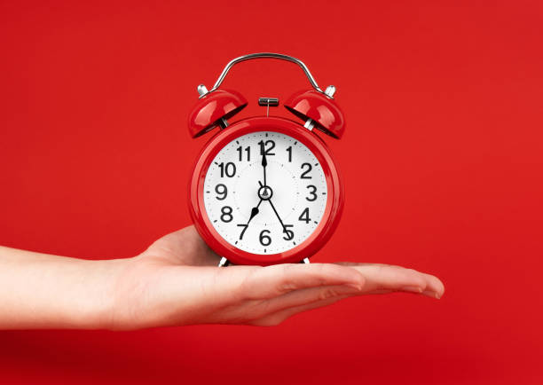 istock A woman's hand holds a red alarm clock against a red background 1491450590