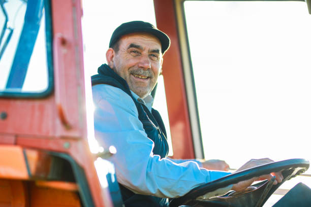 senior farmer drives tractor in the field