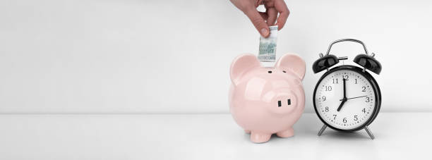 istock Womans hand put dollar bancnote into a piggy bank with alarm clock 1491450638