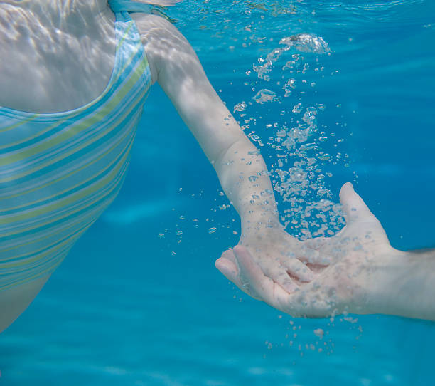 istock Girl (3-5) in pool, touching father's hand, underwater view, clo 149145112