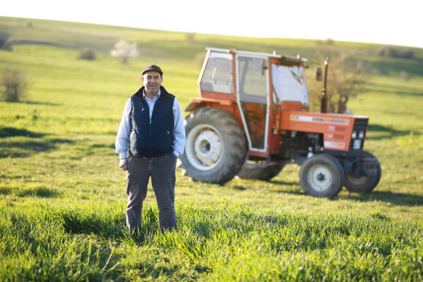 istock senior farmer standing in front of his orange tractor 1491451357