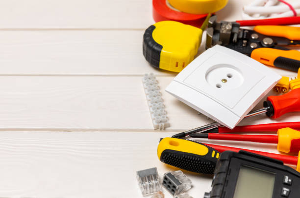 istock Electrician tools on white wooden background.Multimeter,construction tape,electrical tape, screwdrivers,pliers,an automatic insulation stripper, socket and LED lamp.Flatley.electrician concept. 1491452943