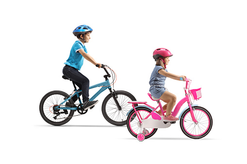 Full length profile shot of a boy and girl bicycles and wearing helmets isolated on white background