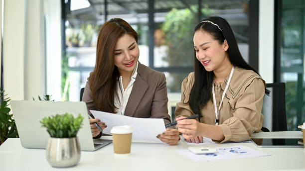 istock Two Asian female colleagues are analyzing financial report and working together. 1491453488