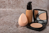 Beauty blender in foundation, concealer composition on white marble background. Makeup artist concept, copy space.