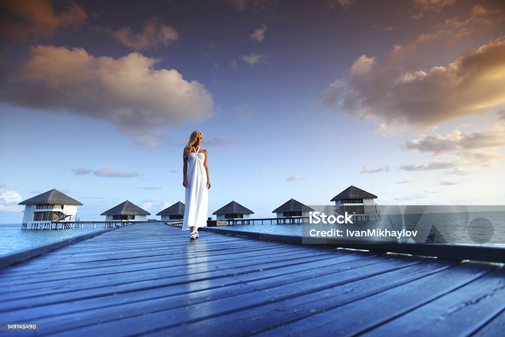 woman in a dress on maldivian sunset woman in a dress on a bridge home sea and the maldivian sunset on the background Adult Stock Photo