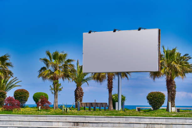 istock Billboard blank for outdoors advertising. Poster banner for advertisement against a clear blue sky and palm trees 1491456046