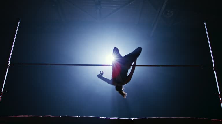 SLO MO LD Female athlete jumping over the crossbar in her high jump practice at night