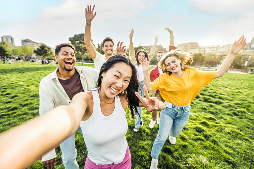 Multiracial group of friends taking selfie picture with smart mobile phone outside - Millenial people enjoying summer day at the park - Life style concept with guys and girls hanging outdoors