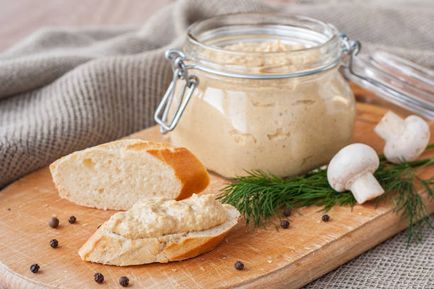 istock Fresh homemade mushroom pate in a jar and on a baguette slice on a rustic background, with champignons and dill. 1491460144