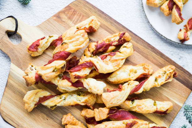 Puff pastry sticks. Close-up of puff pastry with prosciutto. Puff pastry sticks. Close-up of savory puff pastry swirls with prosciutto and olives. Recipe of appetizers idea. High quality photo. twisted bacon stock pictures, royalty-free photos & images