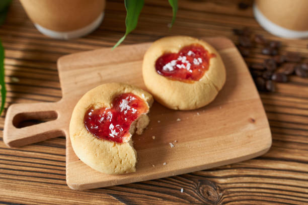 Biscuits with strawberry jam on a wooden table. Biscuits with strawberry jam on a wooden table. Close up, selective focus. Cookie hearts. raspberry jam stock pictures, royalty-free photos & images