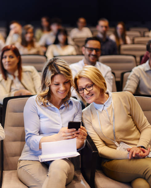 istock Happy businesswomen using mobile phone on a seminar at convention center. 1491461671