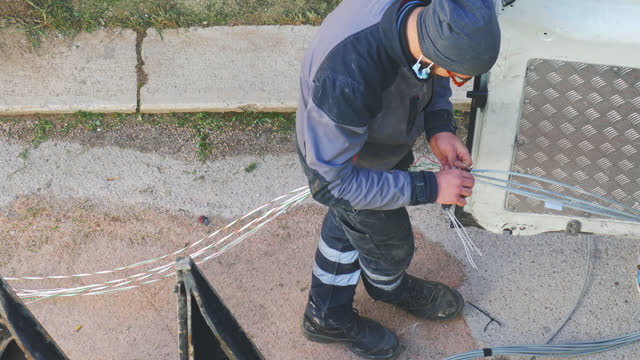 telecommunication technician proceeds with the cabling of fibre optic cables. In particular, individual fibre optic cables are pulled out of the protective sheathing