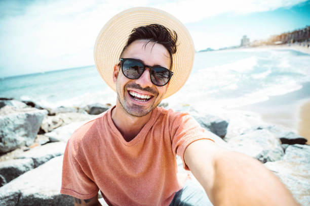 istock Handsome young man taking selfie with smart mobile phone device outside - Cheerful tourist enjoying summertime at the beach - Life style, traveling and technology concept 1491461971