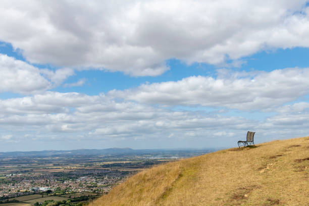 View of a single empty bench on top of Cleeve Hill, Cheltenham, UK along the public footpath Cotswold way with panoramic view on the valley and outskirts of city of Cheltenham