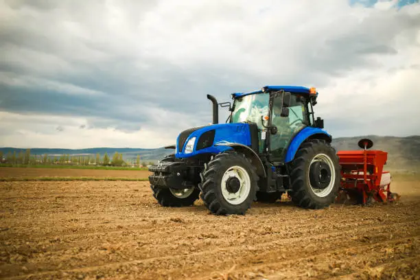 Photo of farmer planting seeds with tractor and seeder