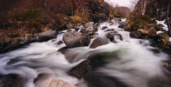 Panoramic view of long exposure of a stream in nature during autumn day.