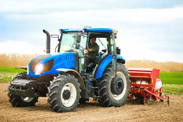 Photo of young farmer planting seeds with tractor and seeder