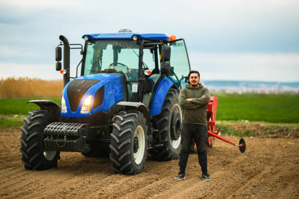 istock young farmer standing in front of tractor and seeder 1491465058