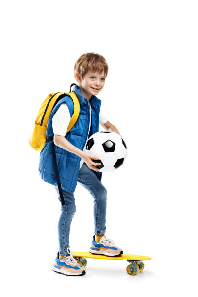 istock Bright little boy with skateboard and backpack holding soccer ball on white background. Back to School. 1491465848