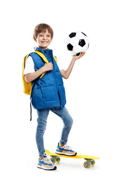 istock Stylish little boy with skateboard and backpack holding soccer ball on white background. Back to School. 1491465849