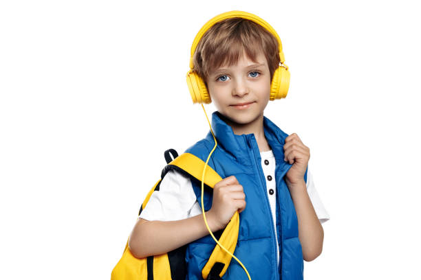 istock Trendy little boy wearing headphone and yellow backpack looking to camera on white background. Back to School. 1491465968
