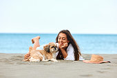 Young woman and her dog enjoying on sandy beach during summer day.
