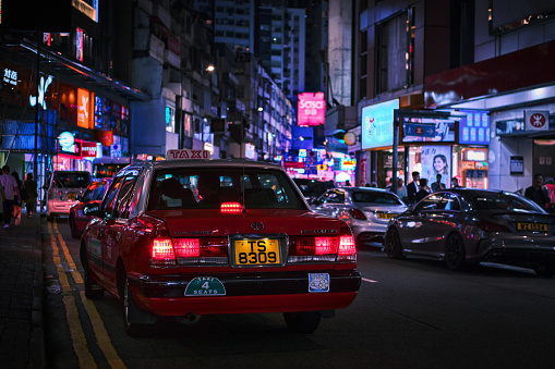 Hong Kong, China - 10 April 2023:  Red Cabs in a street downtown Mong Kok and neon city lights