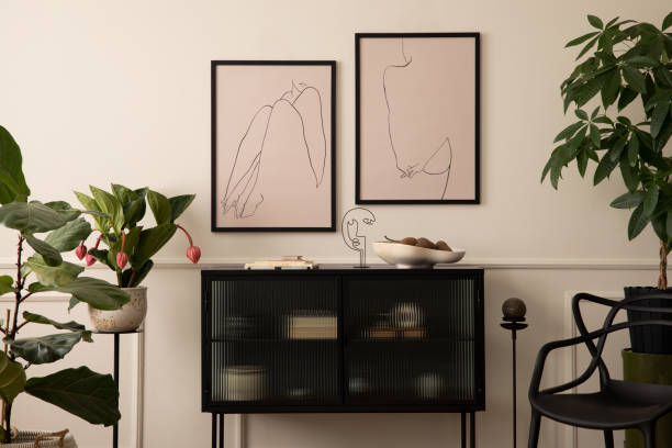 istock Aesthetics composition of living room interior with mock up poster frame, stylish sideboard, beige bowl, black sculpture, plants in flowerpots and personal accessories. Home decor. Template. 1491469108