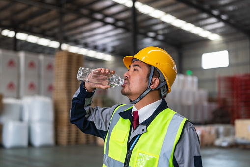 Asian Male Warehouse worker drinking water