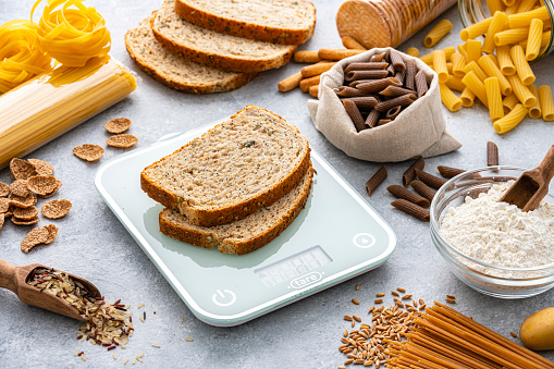 Kitchen scale with two bread slices shot on kitchen table. Carbohydrate food. Dieting concept