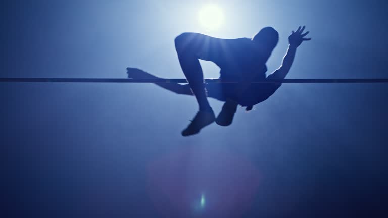 SLO MO LD Male athlete jumping over the crossbar in his night practice