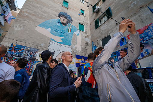Naples, Italy - May 5, 2023: The supporters of the Napoli football team celebrate the victory of the Italian championship in the street. People take selfies in the symbolic place of their all-time idol, Diego Armando Maradona.