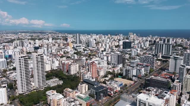 Aerial orbit view of the city center of Santo Domingo. Skyscrapers and office buildings in downtown. Caribbean sea in the background