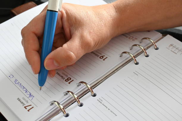 istock Woman's hand writing in an agenda with a blue pen 1491483147