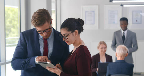 istock Happy business colleagues in modern office working together in tablet pc 1491484229