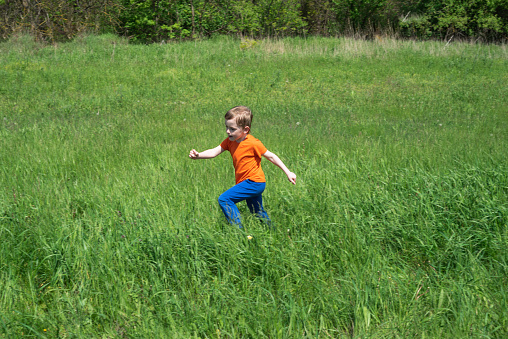 Child outdoors on a sunny day running on the grass. Copy space. International Children's Day concept