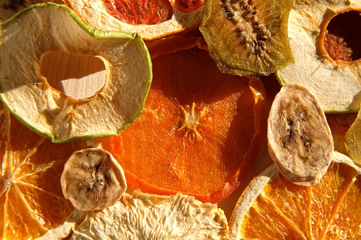 Dried fruits. Assorted of healthy sundried organic fruit spinning on wooden background. Snacking and baking. Trendy Mix of dried and candied fruit slices. Top view, close up. Sunlight hard shadows. 4K. good nutrition. proper diet